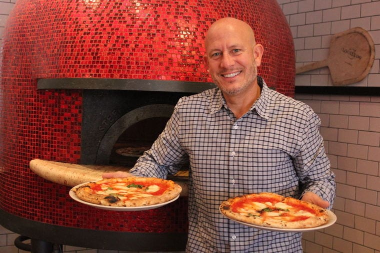 presenting two freshly fired pizzas